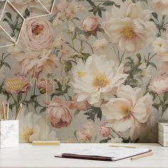 a desk with a notebook, pen and pencil holder on it next to a floral wallpaper