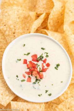 tortilla chips and dip in a white bowl with salsa on the side ready to be eaten