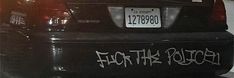 the back end of a black car with graffiti on it's bumper and license plate