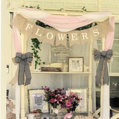 a table with flowers and pictures on it in front of a white building that says flowers