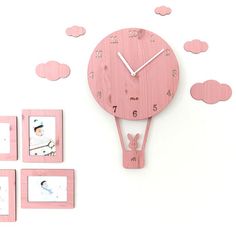 a pink clock with four frames around it on a white surface, surrounded by clouds