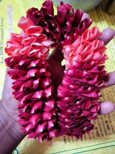 two pink flowers are in the palm of someone's hand on top of a piece of paper