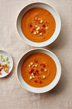 two white bowls filled with soup and garnishes on top of a table