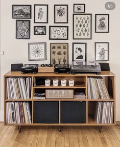 a record player sitting on top of a wooden shelf next to a wall filled with pictures