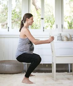 a woman is doing yoga on the floor in front of a desk and chair with her legs crossed