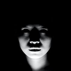 a black and white photo of a woman's face with her eyes closed in the dark