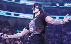 a woman with her arms outstretched in front of an audience at a wrestling match,