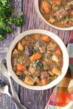 two bowls filled with beef stew on top of a wooden table