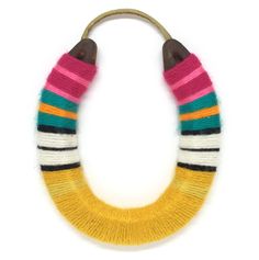 a multicolored necklace is hanging on a white wall and it's wooden handle