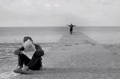 a man sitting on top of a pier next to the ocean