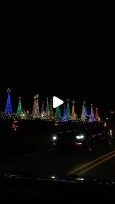 a car driving down the road with christmas lights on it's sides and trees in the background