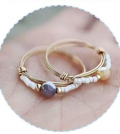 two rings with beads on them sitting on top of a person's hand