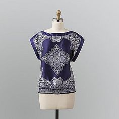 a mannequin wearing a blue and white top with an ornate design on it