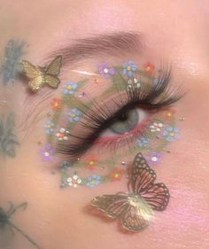 a woman's eye with butterflies and flowers painted on her face, as if it were in the form of a butterfly