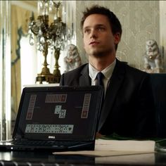 a man in a suit sitting at a desk with a laptop computer on his lap