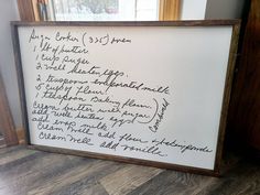 a white board with writing on it in front of a window and wood flooring