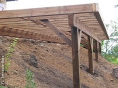 a wooden pergola sitting on top of a hill next to a tree filled hillside