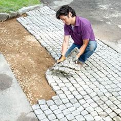 a man is digging in the ground with a brick paver and shovel to build a walkway