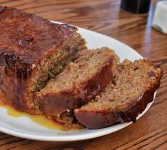 sliced meatloaf on a white plate sitting on a wooden table