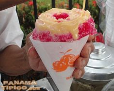 a person holding an ice cream sundae in their hand with fruit on the top