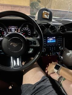 a person sitting in the driver's seat of a car with their feet on the steering wheel