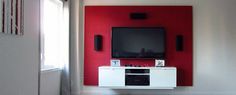 a flat screen tv sitting on top of a white cabinet in front of a red wall