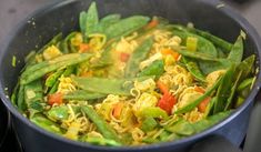 a pot filled with noodles and vegetables on top of a stove