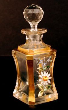 a glass vase with a flower painted on it's side and an acrylic top