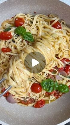 a bowl full of pasta with tomatoes and basil