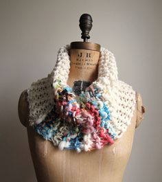 a mannequin wearing a multicolored knitted scarf on top of a dummy