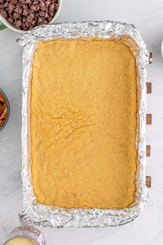 an uncooked pie sitting on top of a table next to bowls of cereal