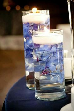 two vases filled with blue flowers and lit candles