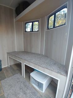 the inside of a mobile home with two windows and a bench in front of it