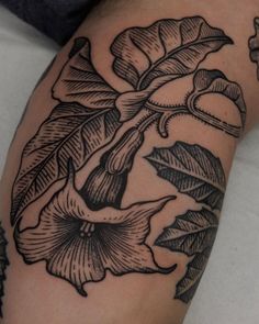 a black and white photo of a flower on someone's left arm with tattoos