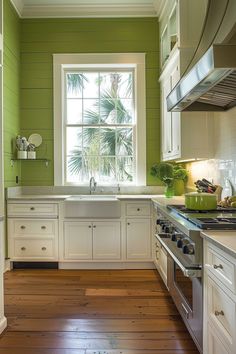 a kitchen with green walls and white cabinets is pictured in this image from the inside