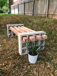 a wooden bench sitting in the grass next to a potted plant