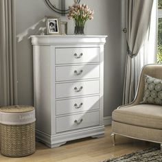 a white dresser sitting next to a window in a living room