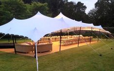 a large white tent set up in the middle of a field with chairs and tables under it