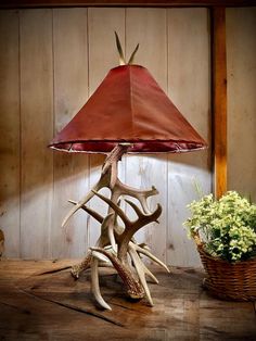 the antler lamp is next to a basket with flowers on it and a potted plant