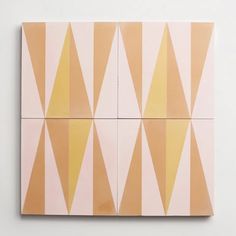 an abstract painting with yellow and pink triangles on it's sides, against a white wall