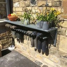 there is a shelf with some plants on it and several boots hanging from the wall