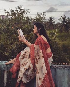 a woman sitting on a ledge reading a book