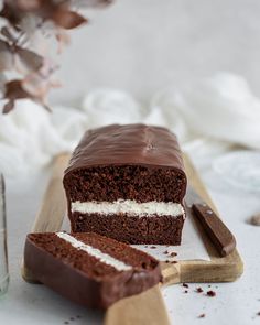 a piece of chocolate cake with white frosting on a cutting board next to a knife