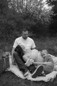 a man and woman sitting on a blanket with two small children