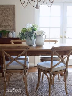 the dining room table has two chairs and a vase with flowers in it on top