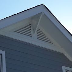 a bird is perched on the roof of a house with a blue sky in the background