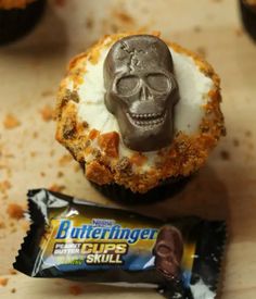 a chocolate skull sitting on top of a cupcake next to a bar of butterfinger chips