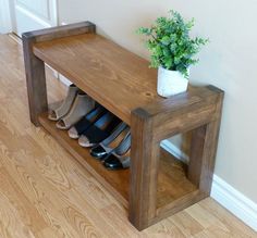 a wooden bench with several pairs of shoes on it next to a potted plant