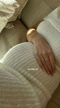 a woman's hand resting on the back of a couch with her arm wrapped in a sweater