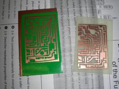 two pieces of copper and green paper on top of a piece of paper with some type of circuit board printed on it